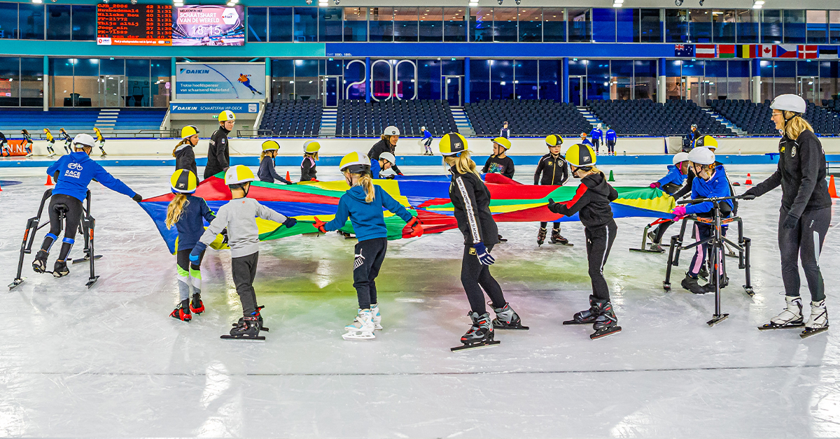 kinderen houden een parachute vast en schaatsen een rondje