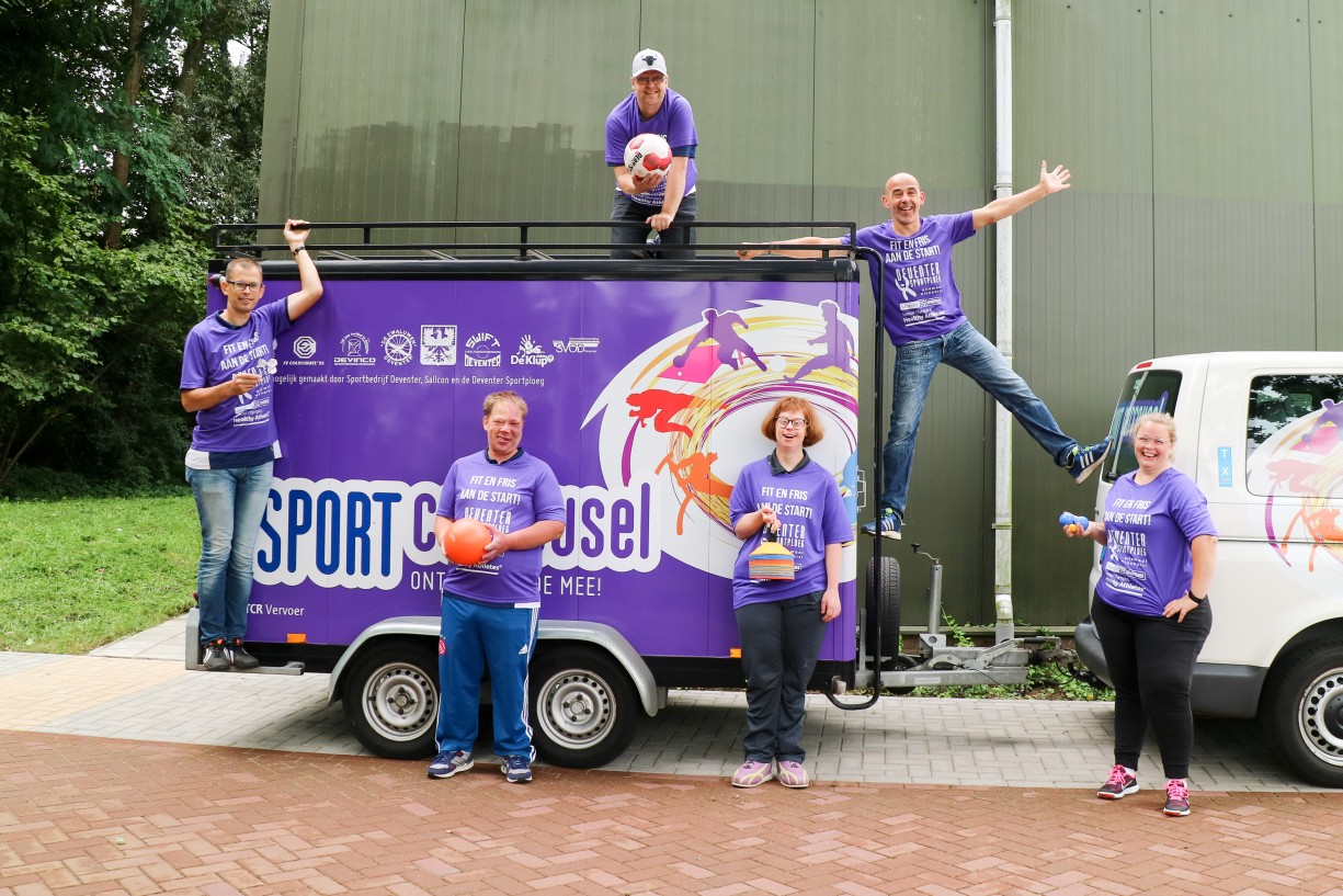 Zes vrijwilligers voor en op de aanhangwagen van de Sportcarrousel van de sportcarrousel